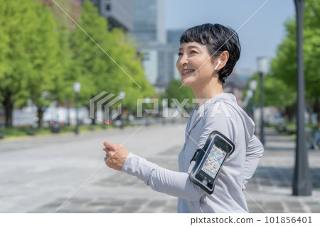 A middle-aged woman jogging in a park in an office district A middle-aged woman jogging in a park in an office district 101856401