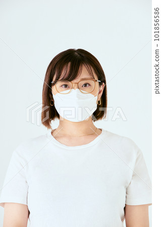 Front view of the upper body of a single Japanese woman in her thirties wearing a mask and glasses looking at the camera on a white background 101856586