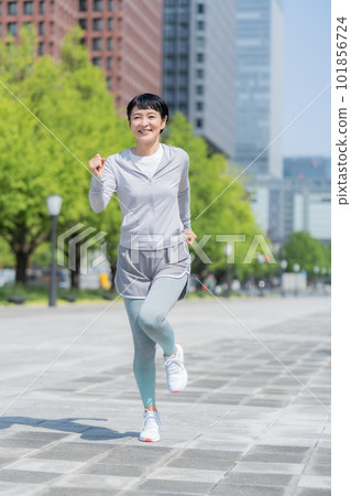中年婦女在辦公區公園慢跑垂直姿勢 中年婦女在辦公區公園慢跑垂直姿勢 101856724