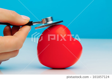A doctor with stethoscope examining red heart, isolated on blue background 101857124