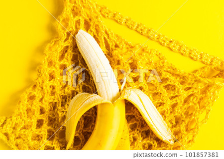 A string bag with bananas isolated on a yellow background. 101857381