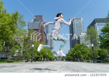 A middle-aged woman jumping in a park in an office district 101857970