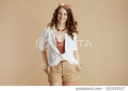 smiling woman in blouse and shorts isolated on beige 101858327