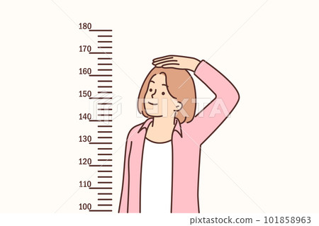 Teenage girl measures height standing near marks on wall, wanting to become tall 101858963