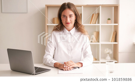 Office worker. Elegant woman. Stylish look. Smiling lady in white shirt sitting desk with documents laptop in light room interior. Office worker. Elegant woman. Stylish look. Smiling lady in white shirt sitting desk with documents laptop in light room interior. 101859886