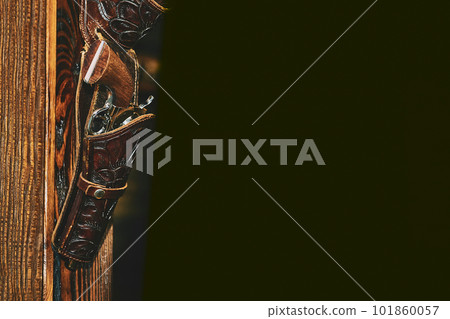 Gun pistol colt revolver in a holster on a wooden wall.Black space for text 101860057