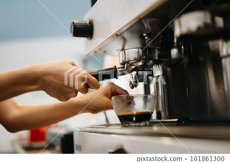 Cup and professional espresso machine pouring fresh coffee into a glass cup at cafe Cup and professional espresso machine pouring fresh coffee into a glass cup at cafe 101861300