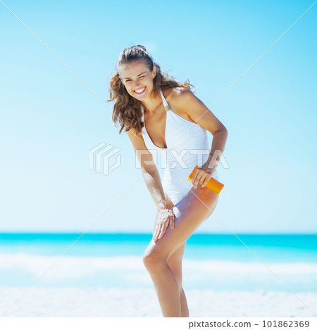 Young woman on beach applying sun block creme 101862369