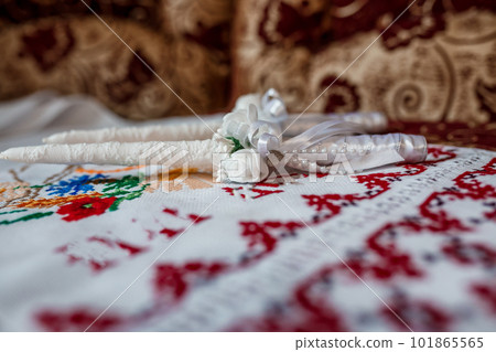 Wedding accessories on an embroidered towel, white candles for church, boutonnieres for guests Wedding accessories on an embroidered towel, white candles for church, boutonnieres for guests 101865565
