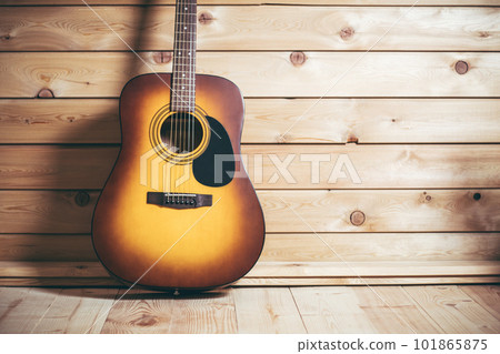 Acoustic six-stringed yellow-brown guitar standing near wooden wall. Copy space. 101865875