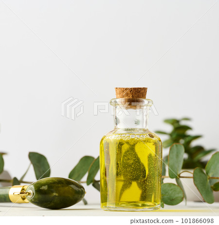 Transparent glass bottle with yellow oil and eucalyptus branch, cosmetic product Transparent glass bottle with yellow oil and eucalyptus branch, cosmetic product 101866098