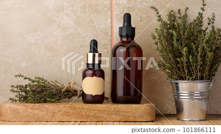 Thyme essential oil in glass bottle with dropper and fresh thyme sprigs on table, cosmetic ingredient Thyme essential oil in glass bottle with dropper and fresh thyme sprigs on table, cosmetic ingredient 101866111