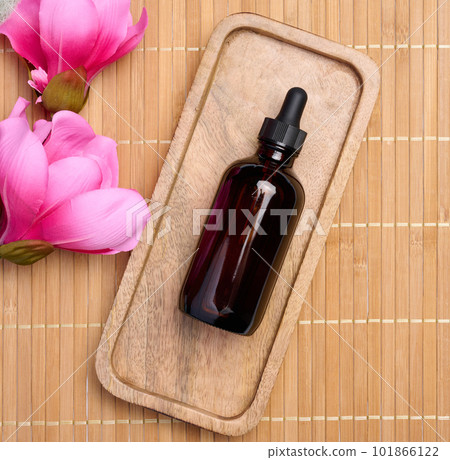 Brown glass bottle with a pipette on a wooden stand, top view 101866122