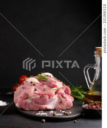 A piece of pork ham on a black board and spices olive oil, salt, rosemary branch and pepper A piece of pork ham on a black board and spices olive oil, salt, rosemary branch and pepper 101866318