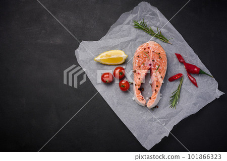 Raw piece of salmon with spices is lying on parchment paper, top view Raw piece of salmon with spices is lying on parchment paper, top view 101866323