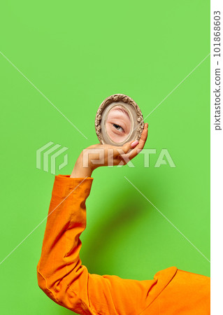Elegant female hand holding small mirror with reflection of girl's eye with makeup isolated over bright green background. Eyelash extension Elegant female hand holding small mirror with reflection of girl's eye with makeup isolated over bright green background. Eyelash extension 101868603