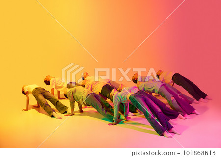 Portrait with group of teenagers, young dancers laying on floor in figures together over pink and yellow gradient background in neon light. Modern dance style Portrait with group of teenagers, young dancers laying on floor in figures together over pink and yellow gradient background in neon light. Modern dance style 101868613