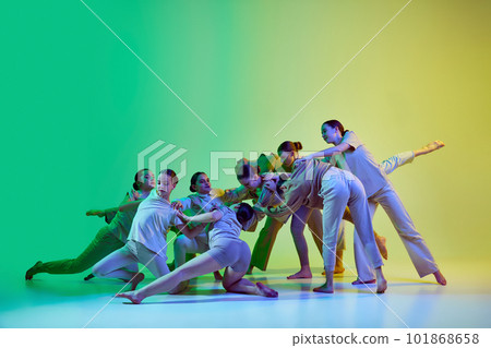 Group of beautiful school girls wearing white clothes dancing together on gradient background in neon light. Contemporary dance style 101868658