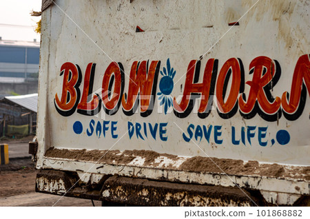 Blow Horn Safe Drive Save Life written on back of a car. 101868882