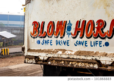 Blow Horn Safe Drive Save Life written on back of a car. 101868883