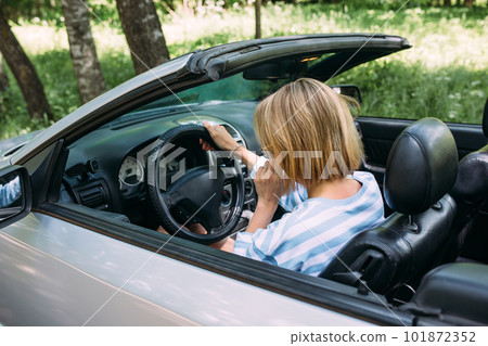 A woman is driving a convertible car. Summer road trip to nature A woman is driving a convertible car. Summer road trip to nature 101872352