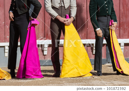 Tourada - bullfighters standing on the arena holding bright tags 101872392