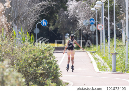 A woman rides roller skates in the park - signs indicating the path for a bicycle and a parent with a child 101872403