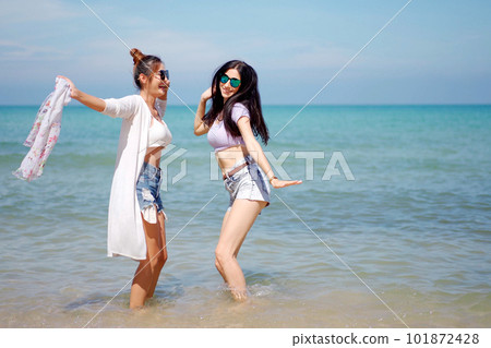 Happy female couple or bisexual couple enjoy walking along the beach together, women holding a hands together and running along the beach. LGBTQ people concept. Happy female couple or bisexual couple enjoy walking along the beach together, women holding a hands together and running along the beach. LGBTQ people concept. 101872428