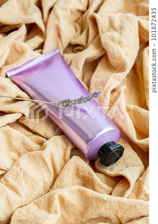 Cosmetic tube and lavender flower on textile background. Cosmetic tube and lavender flower on textile background. 101872435