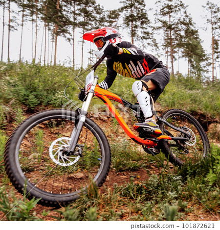 close-up racer athlete riding downhill race in mountain bike, on him protection knee and shin guard, helmet close-up racer athlete riding downhill race in mountain bike, on him protection knee and shin guard, helmet 101872621
