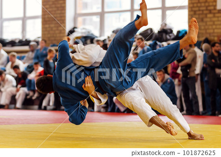 judoka in white kimono landing back his opponent in blue kimono, judo fight competition 101872625