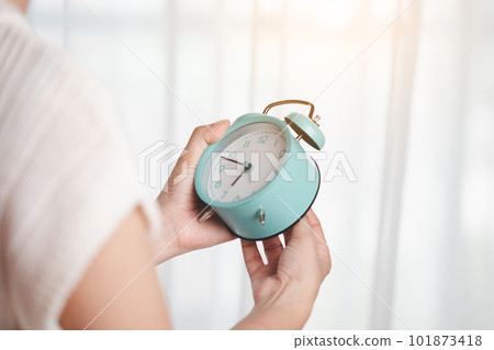 Woman's hand setting the time at the clock to set a reminder or set an alarm 101873418