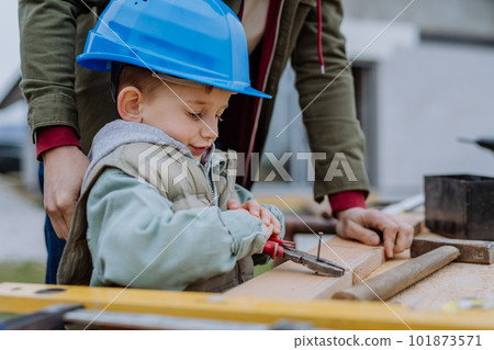 Father and his little son working in front of their unfinished house. Father and his little son working in front of their unfinished house. 101873571