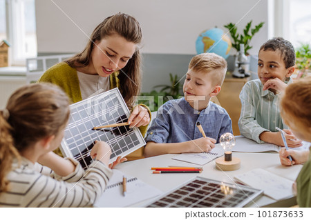 Young teacher with solar panel learning pupils about solar energy. 101873633