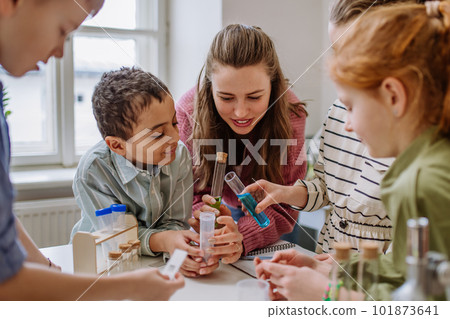 Young teacher doing chemistry experiment with pupils during science education. 101873641