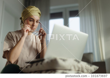 Young woman with cancer working on laptop in her apartment. 101873697