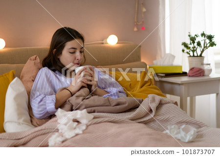 Sick teenage girl laying in bed with cup of tea. 101873707
