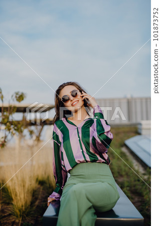 Portrait of beautiful young woman with smartphone outdoor in city, during sunset. 101873752