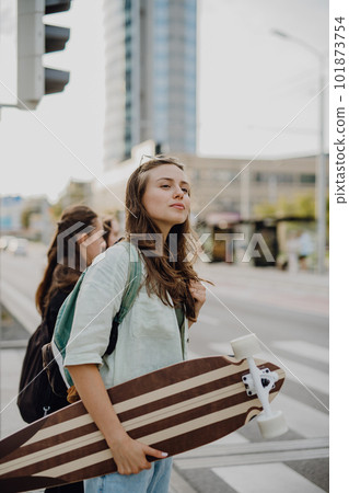 Young woman walking in city with skateboard. Youth culture and commuting concept. 101873754