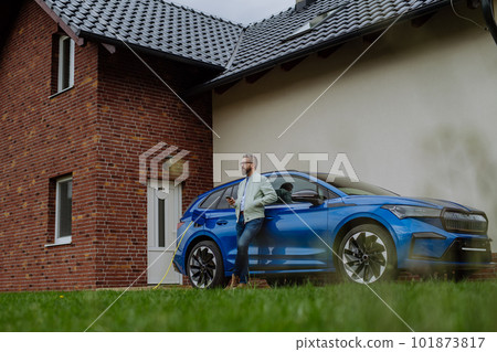 Mature businessman waiting for charging his electric car. 101873817