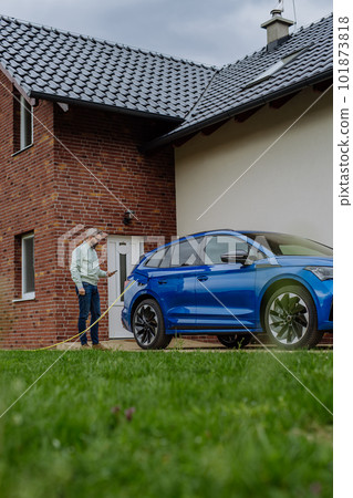 Mature businessman waiting for charging his electric car. Mature businessman waiting for charging his electric car. 101873818