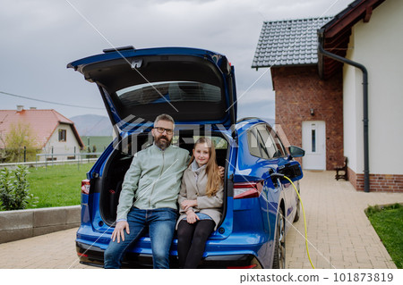 Father and his daughter waiting for charging their electric car. Father and his daughter waiting for charging their electric car. 101873819