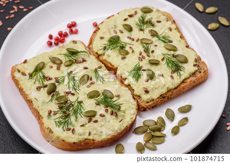 Grilled toast with avocado paste, eggs, cream cheese, salt, spices and herbs 101874715