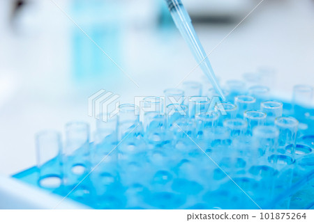 Unrecognizable scientist dripping blue liquid from pipette into test tube at table in laboratory. 101875264