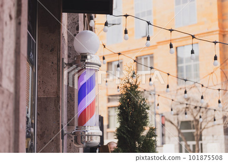 Barber sign and male hairdresser pole or staff mounted on wall. Helix of colored stripes red white and blue 101875508