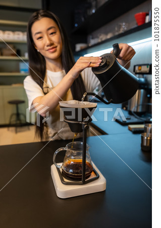 Happy barista posing for the camera while making pour-over coffee Happy barista posing for the camera while making pour-over coffee 101875550