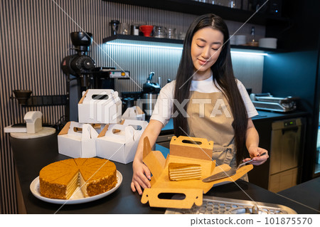 Young cafe worker packing pastry for takeaway Young cafe worker packing pastry for takeaway 101875570