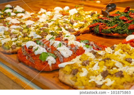 Different kinds of pizza on the wooden desk in the pizza restaurant. 101875863