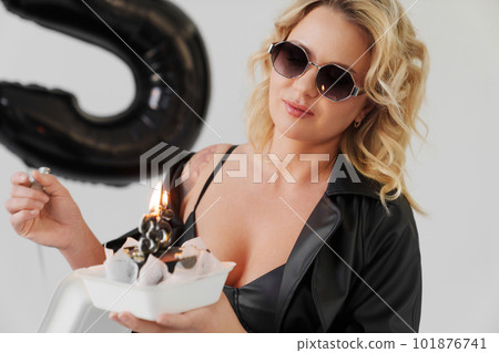 woman in sunglasses lights candles number thirty-five on the cake  101876741