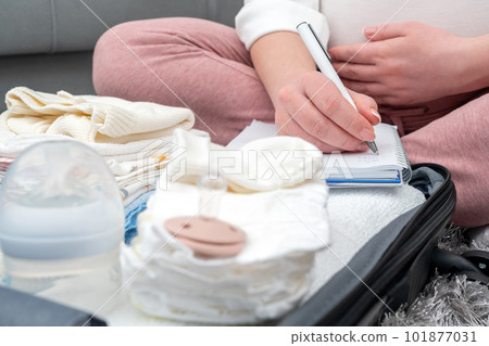 Pregnant woman writing list of things for maternity hospital. Concept of expecting a baby Pregnant woman writing list of things for maternity hospital. Concept of expecting a baby 101877031